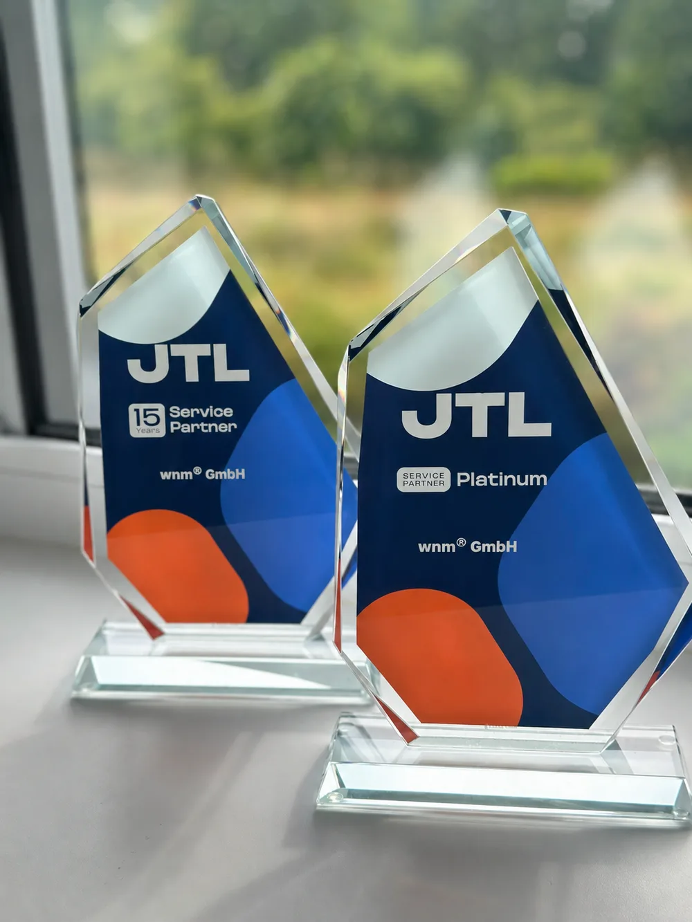 Zwei JTL-Glastrophäen für die wnm GmbH: 15 Years Service Partner und Service Partner Platinum