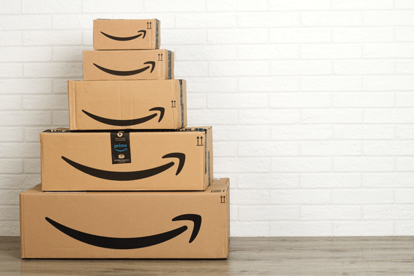 Gestapelte Amazon-Pakete vor weißer Wand