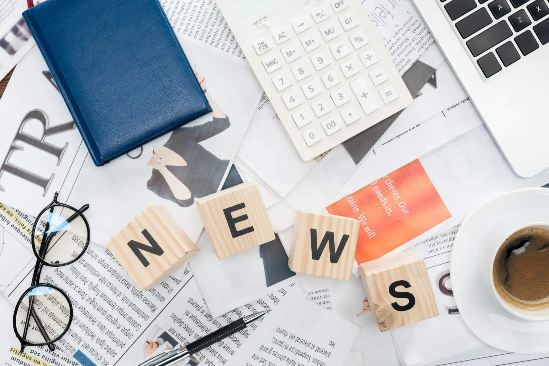 top view of wooden cubes with word news, laptop and calculator on newspapers