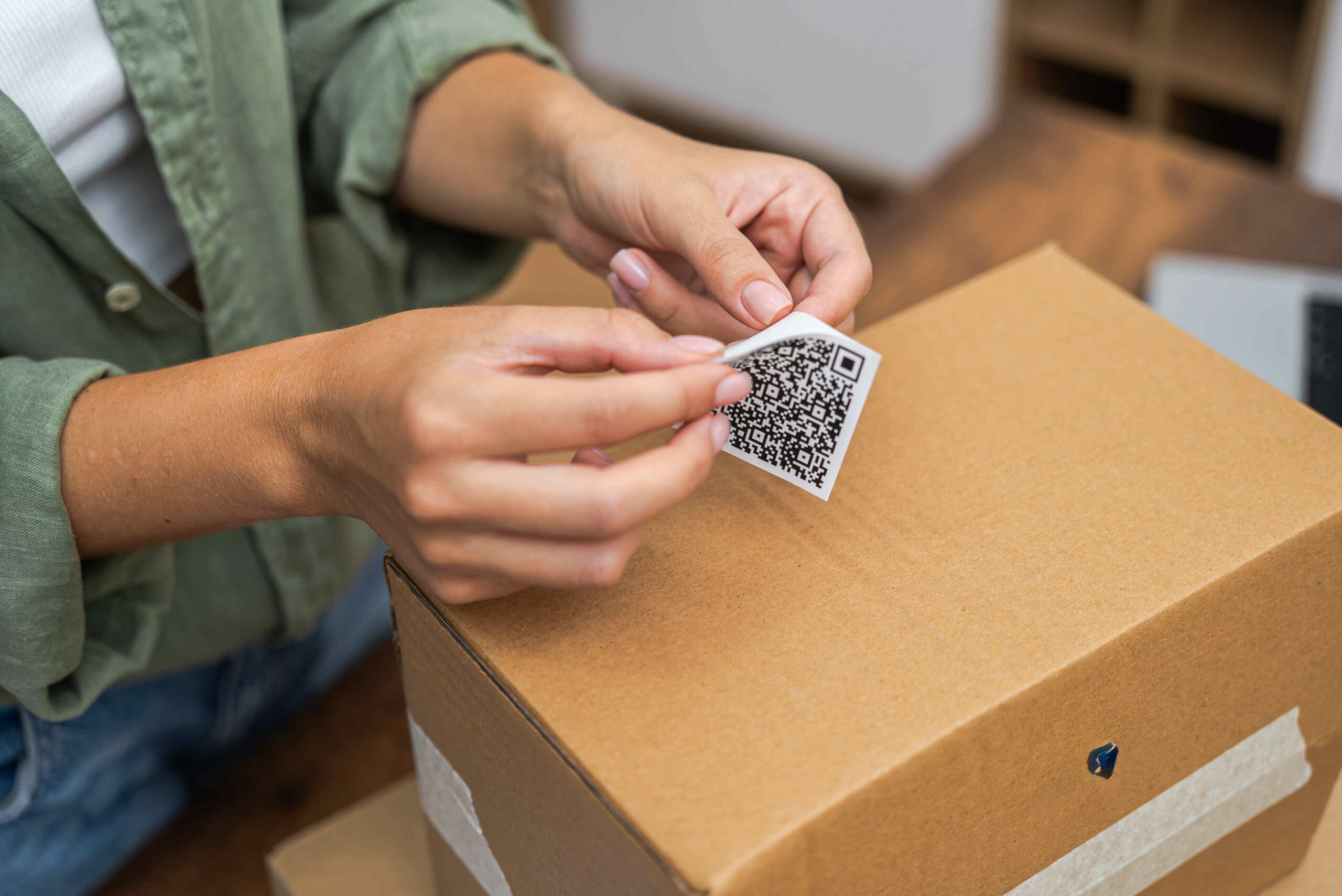 close up With precision, a woman online shopper attaches a qr code label to a cardboard parcel, signaling her intent to return and receive a refund.